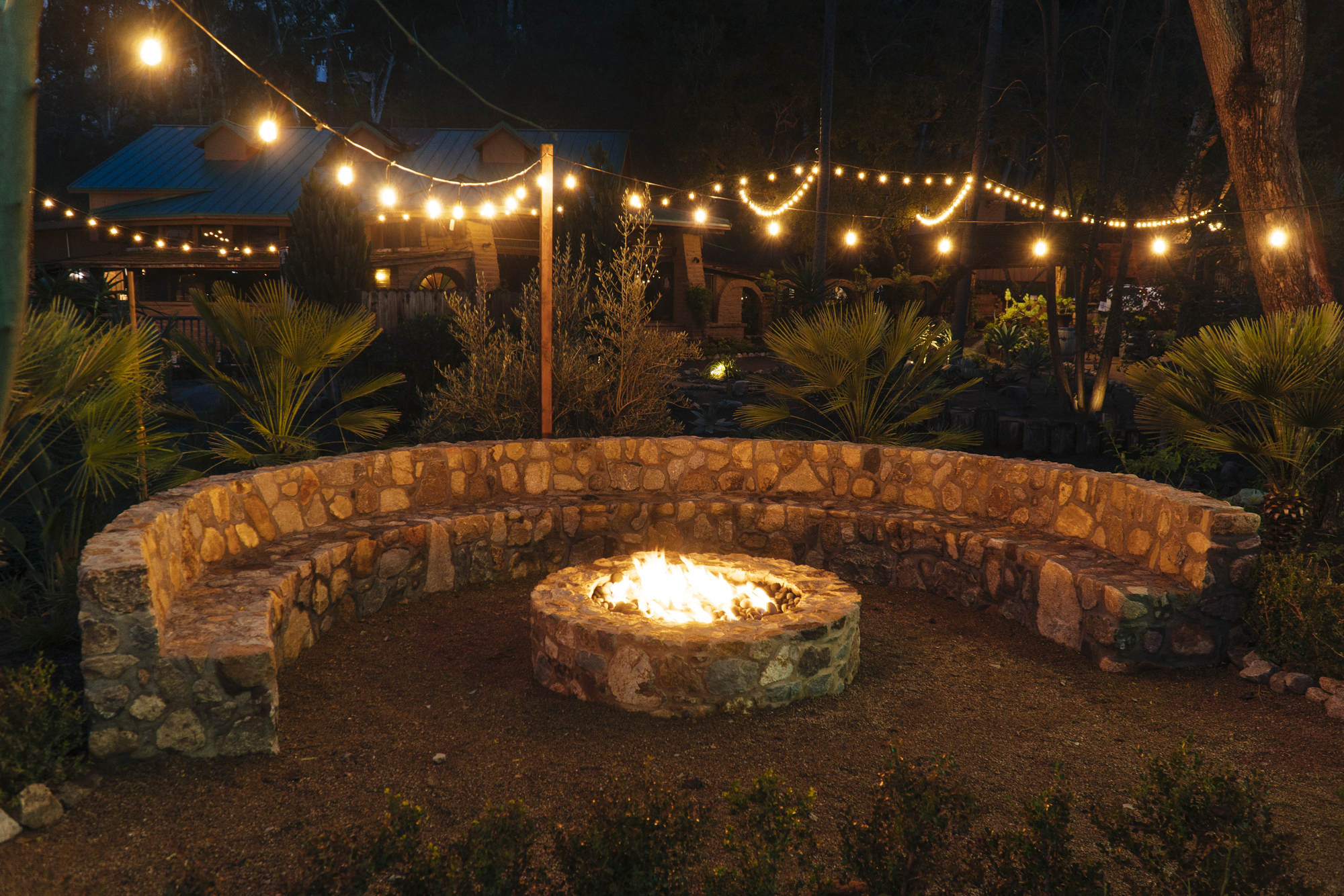 Lit fire pit at night next to sitting wall