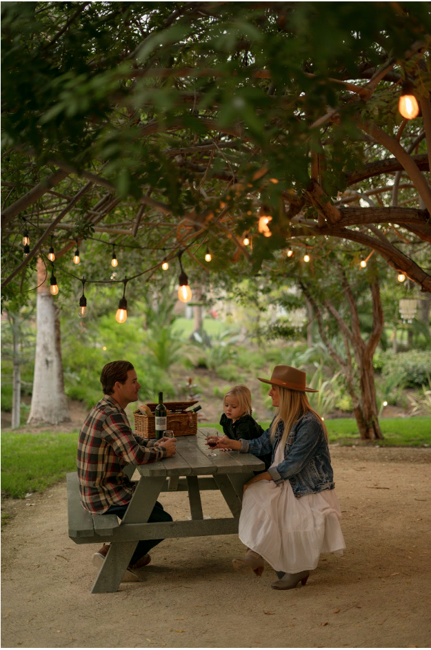 Small family enjoying a drink while sitting under string light tree